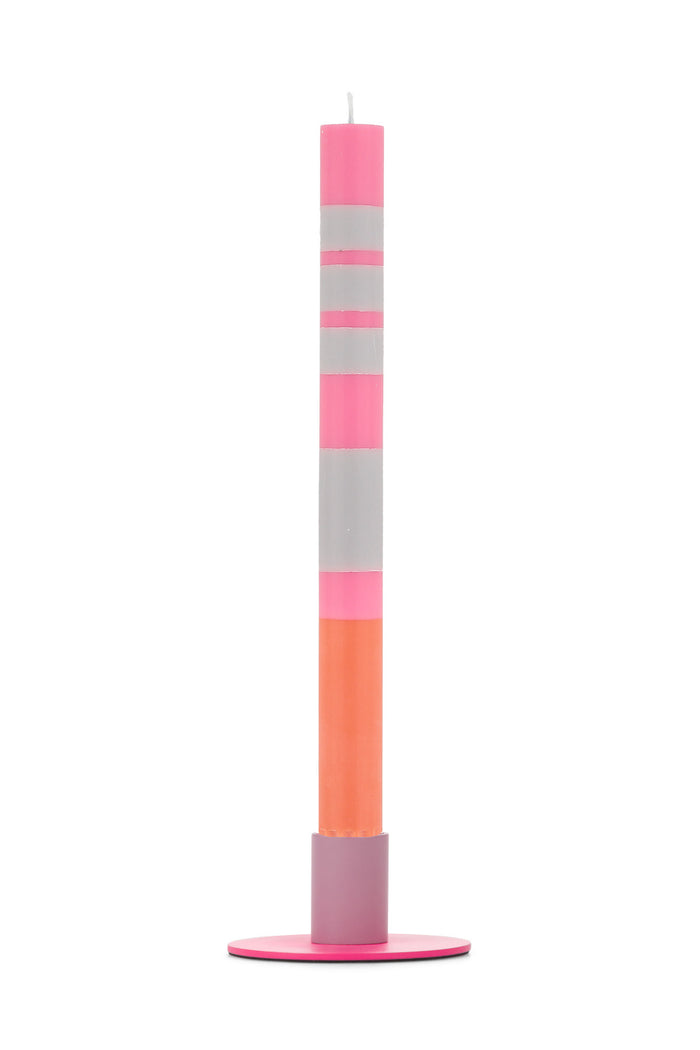 Tall colorful candle with stripes in a modern two-tone metal holder on a flat round base