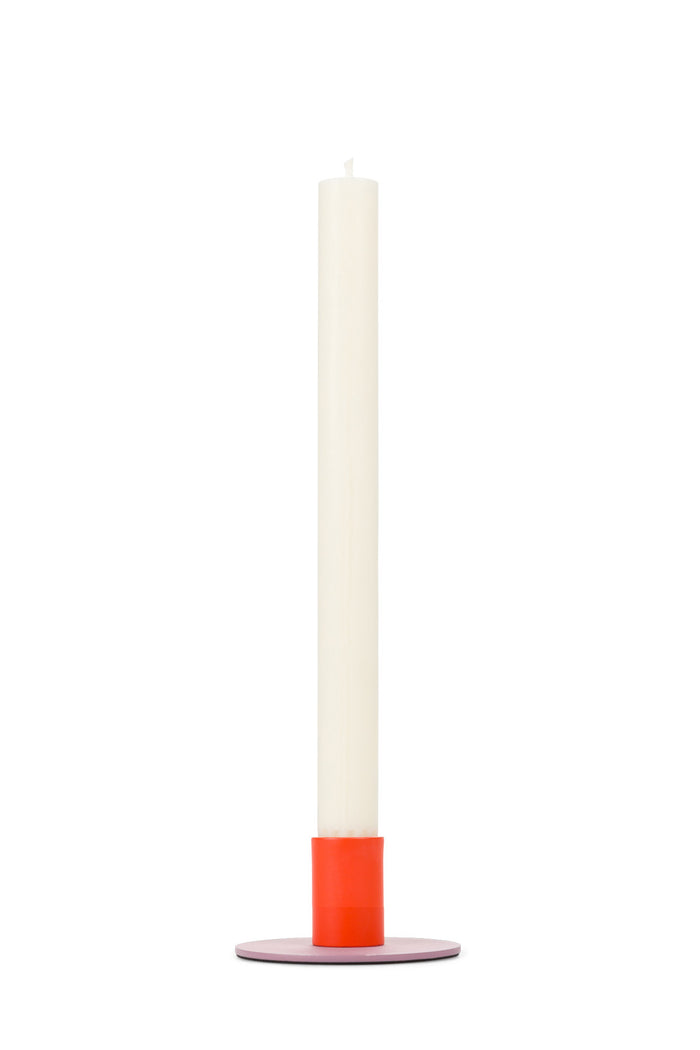 White taper candle in a modern metal two-tone holder with red and purple accents on a white background