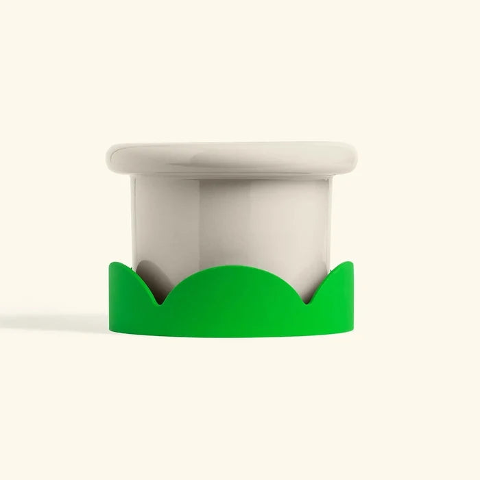 Green silicone petal-shaped drip tray under a white ceramic pot for home decor or plants.