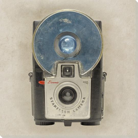 Close-up of a vintage camera with large circular flash, showcasing retro design and metal details on neutral background