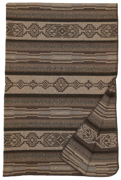 Brown and beige wool blanket with geometric tribal patterns and folded corner showing texture and thickness