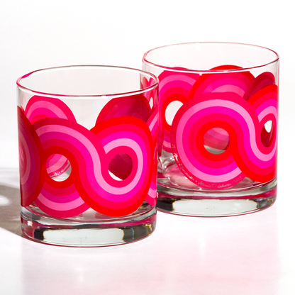 Two clear rocks glasses with bold red and pink circular patterns, ideal for modern home decor or gifts.